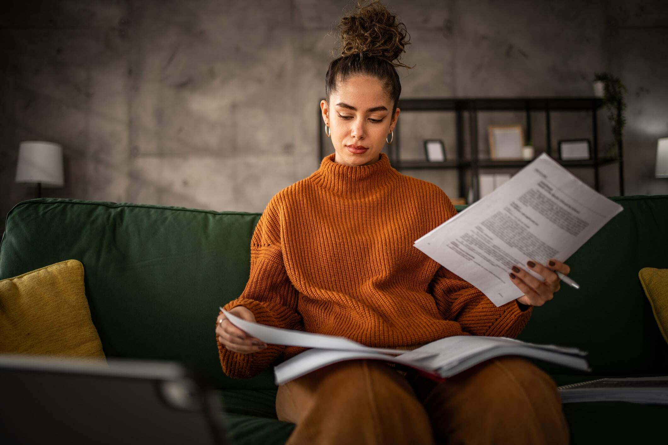 A woman in a sweater is reading through paper documents