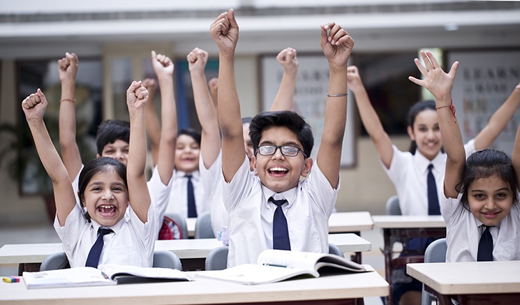 Niños levantando las manos en el aula