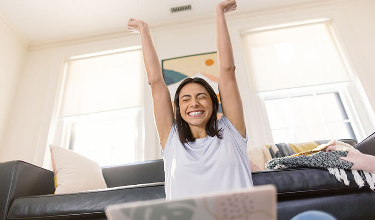 ノートパソコンの前に座り、腕を上げて微笑む女性学生
