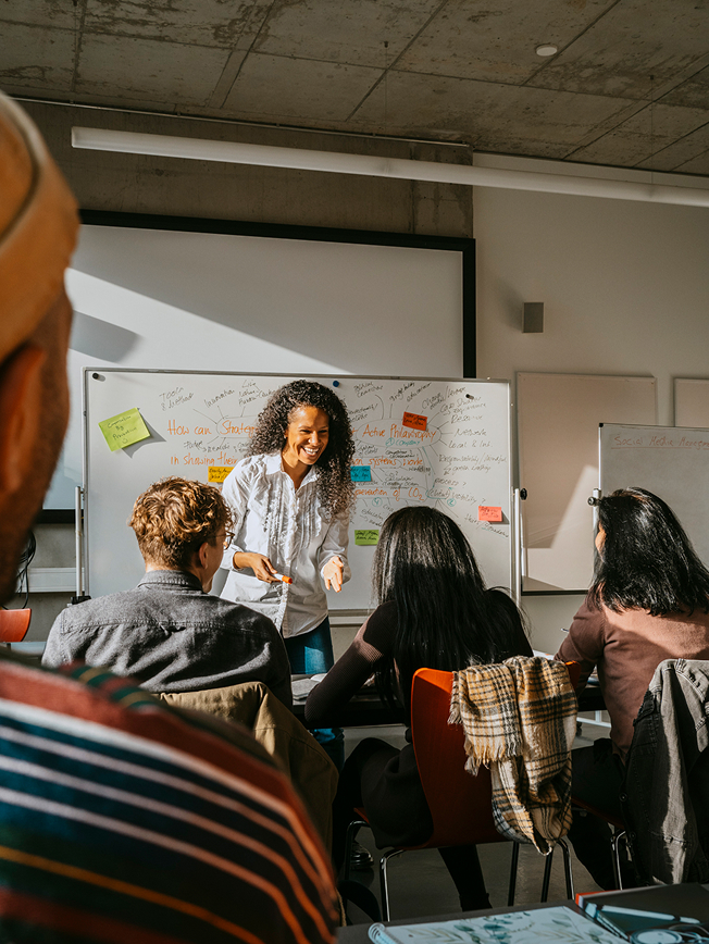 An instructor presenting a lesson to students in a classroom with a whiteboard.