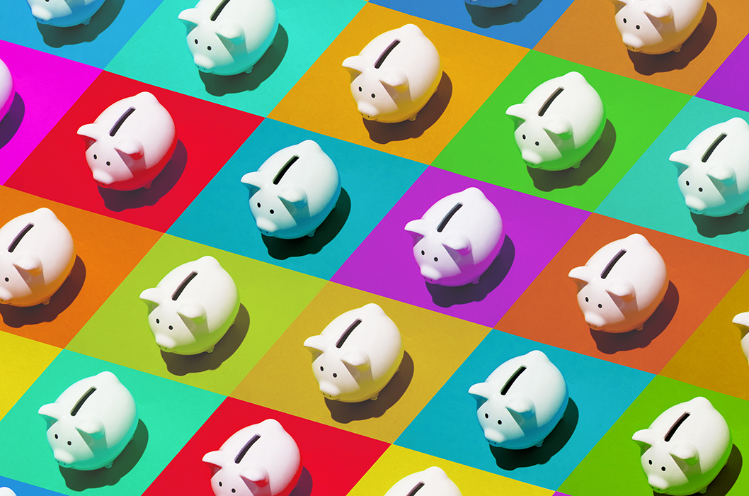 Little white ceramic piggy banks on multi-colored grid, high angle of view