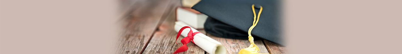 Graduation hat, diploma, and stack of books on wooden table