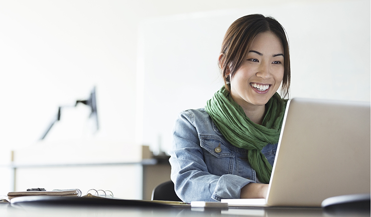 Una mujer sonriendo y viendo una computadora portátil